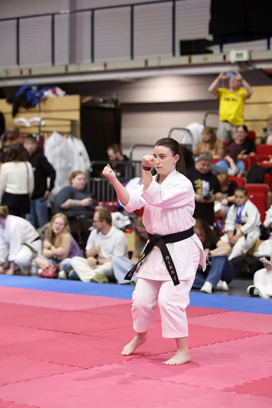 A competitor at the end of a kata, fists set, holding the final position.